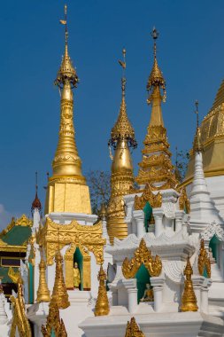 Açık mavi gökyüzünün altında detaylı oymalarla süslenmiş göz kamaştırıcı altın ve beyaz bir koleksiyon. Myanmar.