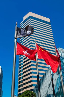 Üç Değişim Meydanı önünde bayraklar dalgalanıyor. Merkez, Hong Kong 'da önde gelen bir ofis binası..   