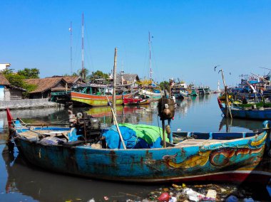 Jepara, Endonezya - 5 Temmuz 2015: Evlerle çevrili, nehir kıyısında renkli tekneleri olan geleneksel bir balıkçı köyü.