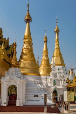 Açık mavi gökyüzünün altında detaylı oymalarla süslenmiş göz kamaştırıcı altın ve beyaz bir koleksiyon. Myanmar.