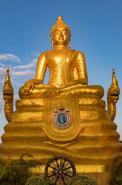 Oturan bir Buda 'nın altın heykeli, parlak mavi gökyüzüne karşı huzur içinde gülümsüyor..