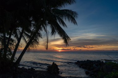 Parlayan ufuk ve sakin deniz dalgalarıyla dolu canlı bir akşam kıyıda, Camiguin, Filipinler