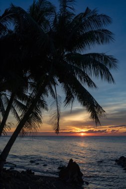 Parlayan ufuk ve sakin deniz dalgalarıyla dolu canlı bir akşam kıyıda, Camiguin, Filipinler