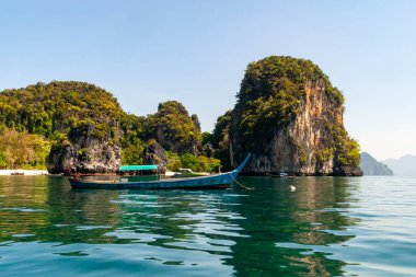 Bereketli kayalık adaların yakınında yüzen geleneksel ahşap tekne güneş ışığını yansıtıyor, Tayland, Yengeç.