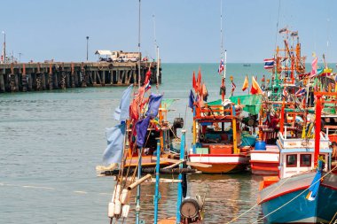 Açık gökyüzü, Tayland ve Krabi 'nin altında ahşap iskeleye yanaşan renkli balıkçı tekneleri.