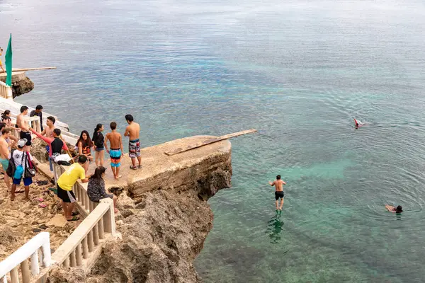 İnsanlar Rocky Ledge, Camotes, Filipinler 'den Temiz Okyanusa Atlayan Bir Kişi İzliyor