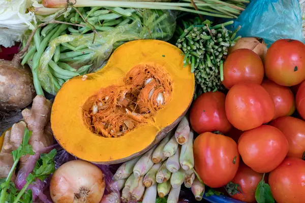 Pazar yerinde balkabağını çevreleyen taze sebzeler.