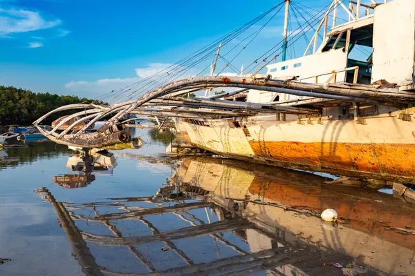 Paslı balıkçı teknesi sakin su kıyısına yansıyor, Filipinler Mactan