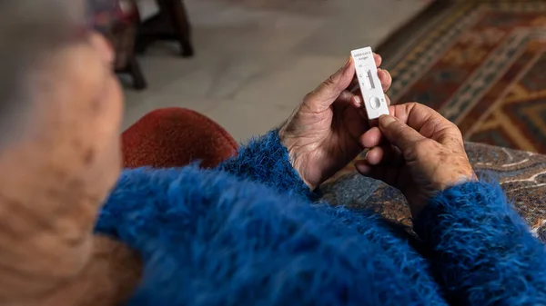 Caucasian grandma makes a rapid home test device for Covid19 virus with a negative result. Grandmother using an antigen cassette of pcr express test for new Omicron variant virus.