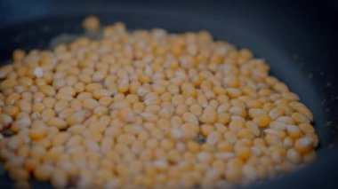 Slowmotion of crunchy popcorn snack. A stainless pan cooking and flying tasty corns grains. Cook delicious and tasty pop corn. Making sweet or salt cinema food commercial.