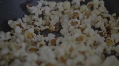 Slowmotion of homemade popcorn popping wildly from a frypan. Crunchy pop corn snack in cooked a pan.  delicious and tasty corns kernels almost popped with salt