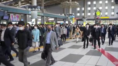 Tokyo, Japonya-12 Nisan 2023: Bir grup işçi metro istasyonundan yaya olarak geçiyorlar. Yoğun bir Japon işçi akıntısı işlerine doğru ilerliyor..