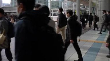 Tokyo, Japonya-12 Nisan 2023: Yüzlerce yolcu Japonya 'daki metro istasyonundan iş yerlerine gitmek için acele ediyor. Kalabalık bir kalabalık kalabalık kalabalık caddede yürüyor.