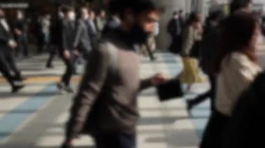 Japonya 'daki metro istasyonundan taşan banliyö sakinlerinin bulanık görüntüsü, hepsi ofislerine doğru aynı yöne gidiyor. Kalabalık bir kalabalık kalabalık kalabalık caddede yürüyor.