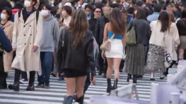Tokyo, Japonya-10 Nisan 2023: Japonya 'da gündüz vakti ünlü Shibuya Geçidi' ni geçen kalabalık kalabalık, yoğun bir şekilde toplanmış ve hızla caddelerde ilerliyordu..