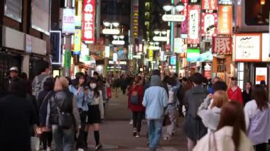 Tokyo, Japonya-10 Nisan 2023: Aydınlatılmış reklam panoları şehir merkezini süslüyor, alışveriş bölgesinde yayaların geceleri ticari caddelerden geçtiği canlı bir atmosfer yaratıyor.