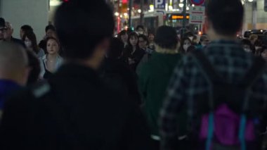 Tokyo, Japonya-10 Nisan 2023: Gece trafiği sırasında caddenin karşısındaki ünlü Shibuya kavşağındaki insanlar. Yayalar ticari caddelerde geceleri dolaşıyorlar.