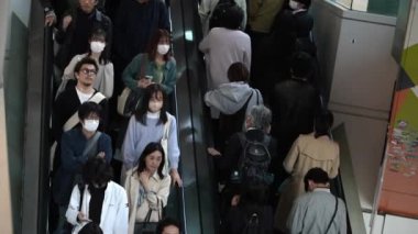 Tokyo, Japonya-10 Nisan 2023: Asyalı bir kalabalık Shibuya bölgesindeki metro yürüyen merdivenlerini dolduruyor. Yoğun saatlerde hareket halindeki merdivenleri kullanan Japon banliyö sakinleri.