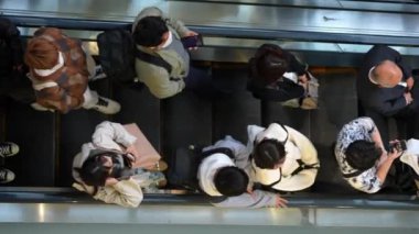Tokyo, Japonya-10 Nisan 2023: Shibuya bölgesindeki metro yürüyen merdiveninde Asya kökenli birçok insanın görüntüsü yükseldi. Yoğun dönemde hareket halindeki adımları takip eden Japon banliyö görevlileri.