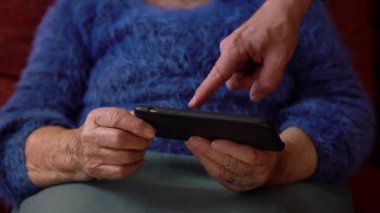 Yaşlı kadının buruşuk elleri akıllı telefon tutuyor. Yeni uygulama ya da web sitesi için telefon kullanan Kafkasyalı büyükannenin yaşlı ellerini kapat.