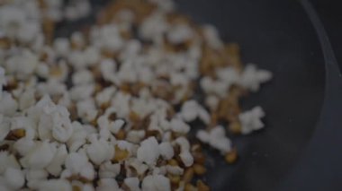 Slowmotion of crunchy popcorn snack. A stainless pan cooking and flying tasty corns grains. Cook delicious and tasty pop corn. Making sweet or salt cinema food commercial.