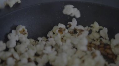 Slowmotion of crunchy popcorn snack. A stainless pan cooking and flying tasty corns grains. Cook delicious and tasty pop corn. Making sweet or salt cinema food commercial.