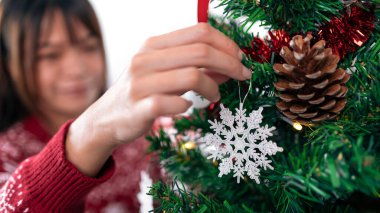 Asyalı bir kadın Noel ağacını güzel bir kar tanesiyle süslüyor. Tatil yıldızı Xmas süsleriyle süslenmiş bir kız. Yeni yıl dekorasyon ögesi