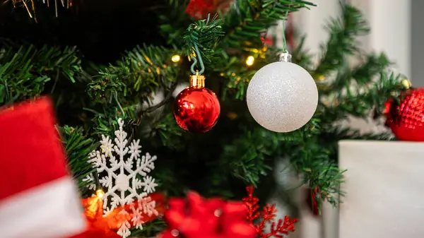 Tasarım için yeri olan şenlikli Noel baloları. Güzel yeşil köknar dalları süsleri ve beyaz pankartta Xmas süslemeleri. Kış noeli konsepti. Yeni yıl arkaplanını görüntüle.