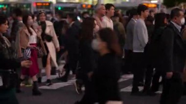 Tokyo, Japonya-10 Nisan 2023: Gece trafiği sırasında caddenin karşısındaki ünlü Shibuya kavşağındaki insanlar. Yayalar ticari caddelerde geceleri dolaşıyorlar.