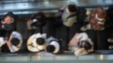 Tokyo 'nun Shibuya bölgesindeki metro yürüyen merdivenlerini dolduran kalabalığın görüntüsü bulanık. Japonya 'da yoğun saatlerde hareket halindeki merdivenleri kullanan Japon banliyö sakinleri