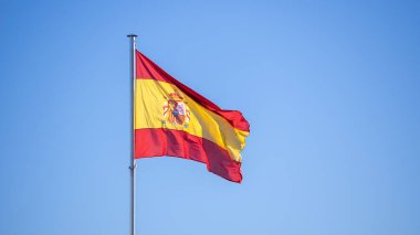 Mavi gökyüzüyle rüzgarda dalgalanan İspanyol bayrağı. İspanya afişi, yumuşak ve pürüzsüz ipek. Kumaş kumaş dokusu, Asteğmen. Ulusal gün ve ülke etkinlikleri konsepti için kullan..