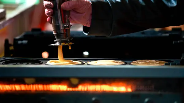 A vendor cooking dorayaki at roadside stands in Asia, the Japanese form of a pancake. These are sold in the streets at night markets in Japan as a popular Asian snack.