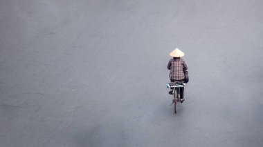 Vietnamlı bir kadının boş bir Hanoi caddesinde bisikletini sürerken görüntüsü mesaj için boş bir fotokopi alanımız var. Geleneksel Asya konik hasır şapkası takıyor. Vietnam Kültür Mirası.
