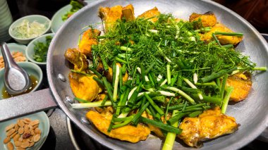 Kemiksiz ızgara hemibagrus balığı. Cha Ca La Vong Hanoi adında kızarmış bir nehir yayın balığı. Taze dereotu ve taze soğanlı restoranlar masası.