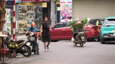 Vietnam, -03 Nisan 2024: Hanoi şehrinde bir yol boyunca seyyar çiçek tezgahlarına dönüşmüş motosikletli Vietnamlı bir sokak satıcısının yavaşlaması. Vietnam Kültür Mirası.