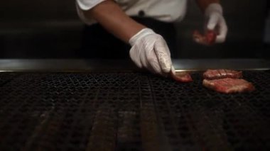 Profesyonel şefin yavaş yavaş pişirmesi birinci sınıf ve taze Wagyu bifteği ince ince dilimlenmiş ve zarif bir restoranda Japon barbeküsü Sukiyaki ile servis ediliyor. Yakiniku Japon usulü et pişirme yöntemi.