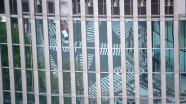 Japon bulvarındaki kavşak yolu ve araba trafiği güneşli bir yaz gününde modern bir iş binasının camına yansıdı. Kentsel ve modern yapı kavramı.