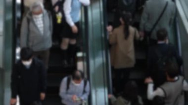 Asyalıların bulanık manzarası Japonya 'da alışveriş merkezinin yürüyen merdivenine biniyor ve Japon müşteriler Tokyo' daki alışveriş çılgınlıkları için yoğun saatlerde hareket halindeki merdivenleri kullanıyor..