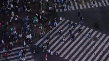 Tokyo, Japonya-10 Nisan 2023 gece Shibuya Geçidi 'nin yukarısından, neon ışıkları ve hareketli aktivitelerle aydınlatılmış. Sayısız insan kavşaktan geçerken bir aktivite kovanına dönüşüyor.