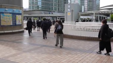 Tokyo, Japonya-12 Nisan 2023: Japonya 'daki metro istasyonundan bir grup insan işe giderken kaldırımları dolduruyor. Japon işçilerin günlük ayini işe gitmek için kalabalık bir yoldu..