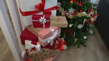 Evdeki modern bir Noel süsleme ağacının altında Noel süslerinin yanında yeni yıl dekorasyonuna katkıda bulunan güzel paketlenmiş hediye kutuları..