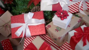 Modern bir Noel ağacının altında, zarif bir şekilde paketlenmiş hediye kutuları, yeni yıl dekorasyonu için bir tasarım unsuru olarak, Noel süslerinin yanı sıra beyaz arka planlı bir evde tatil atmosferini artırır..