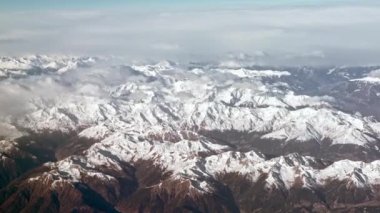 Karla kaplı Alpler 'in hava manzarası, engebeli dağ zirveleri manzarayı kapsıyor. Yüksek rakımlar hafif kar tozlarıyla kaplı, dağlara buzlu bir görünüm kazandırıyor..