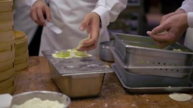 Tayvan şeflerinden oluşan bir ekip geleneksel yemekler pişiriyor. Asyalı şef Tayvan restoranında taze börek yapıyor. Erkekler elleriyle hamur köftesi pişirir ve hazırlarlar..
