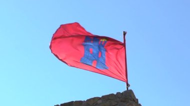 Aracena 'nın ikonik kırmızı bayrağının, İspanya' da açık bir gökyüzüne doğru mavi kale amblemi sallanışının yavaş hareketi. Yerel miras, kültürel gurur ve geleneksel sembolleri temsil ediyor