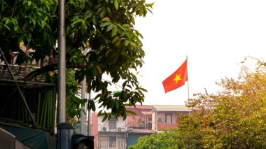 Kızıl Vietnam bayrağı, güçlü bir ulusal semboldür, Hanoi şehrinde bir caddede yüksekte dalgalanır, ülkenin kimliğini, mirasını ve gururunu temsil eder..