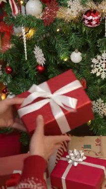 Dikey bir Asyalı kadın Noel için güzel paketlenmiş bir hediye kutusu tutuyor, evinde Noel kutlaması ekliyor, bayram ruhunu canlandırıyor..