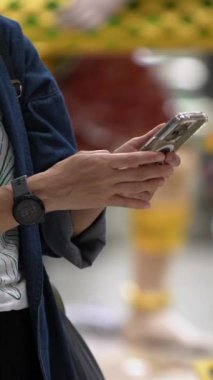Dikey, Gezgin uluslararası havaalanının modern iç kısımlarında akıllı telefon kullanıyor. Seyahatte iletişim ve teknoloji. Bağlantı ve küresel ulaşım için ideal