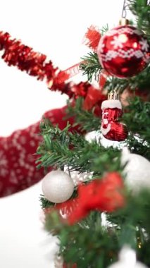 Dikey Mutlu Noeller ve mutlu tatiller, Asyalı bir kadının eli çelenk ağacını evde kışın süslüyor. Dekorasyon için köknar dallarından sarkan Xmas topu