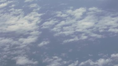 Uçsuz bucaksız mavi gökyüzünü ve ufuk boyunca uzanan beyaz bulutları gösteren ve Dünya atmosferinin güzelliğini ön plana çıkaran bir hava görüntüsü..